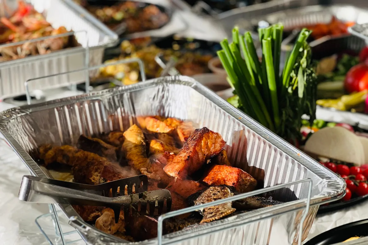 Un bufé de catering con carnes asadas y verduras, representativo de una cena estilo hangi